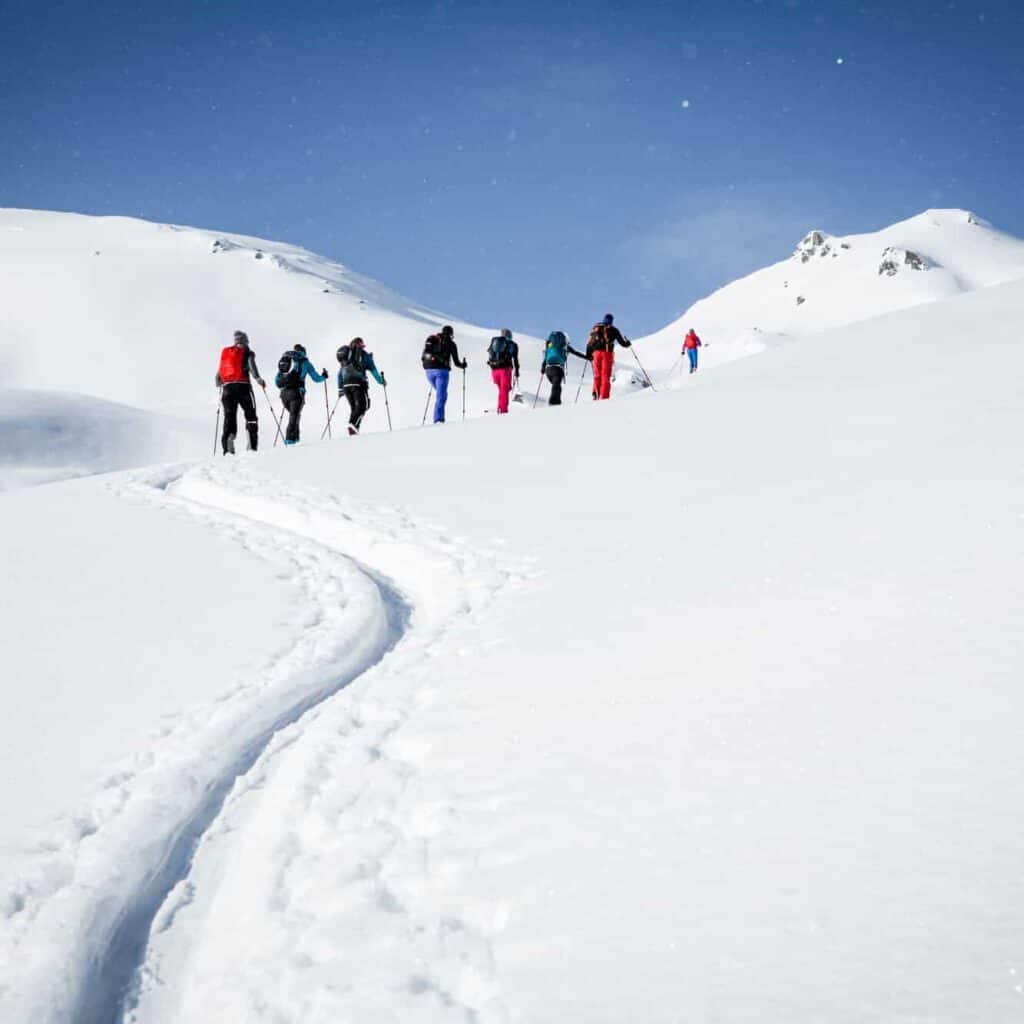 Skitourengruppe wandert durch unberührte Schneelandschaft in den Alpen.