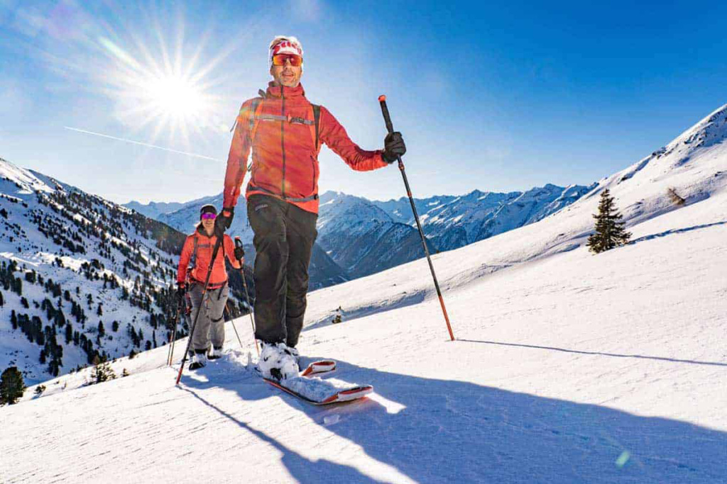 Zwei Skitourengeher erkunden die schneebedeckten Alpen unter strahlender Sonne.