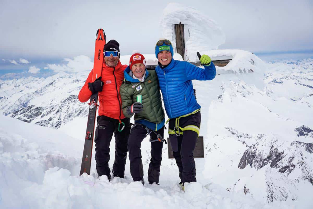 Drei Skibergsteiger freuen sich auf einem schneebedeckten Gipfel in den Alpen.