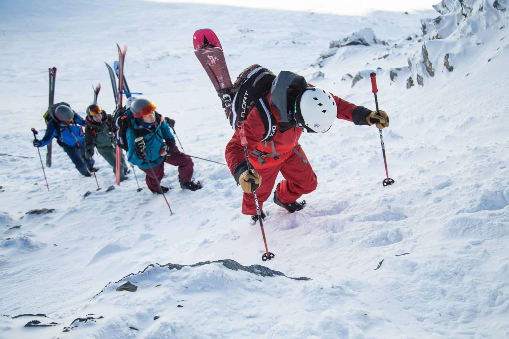 Skitourengeher erklimmen verschneite Bergpisten in den Alpen mit Ausrüstung und Stöcken.