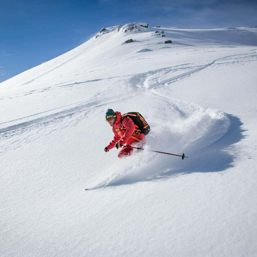 Skitourengeher fährt durch frischen Schnee in den Alpen, ideal für Winterabenteuer.