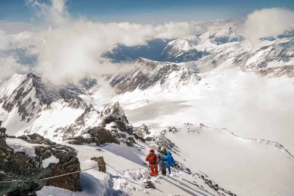 Bergsteiger durchqueren schneebedeckte Alpenlandschaft auf dem Weg zum Gipfel.