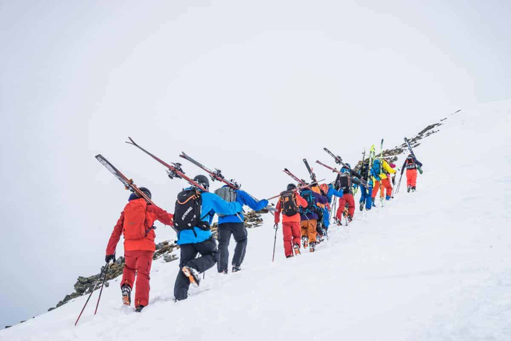 Gruppen von Skitourengehern ziehen mit Ski über verschneite Hänge in den Alpen.