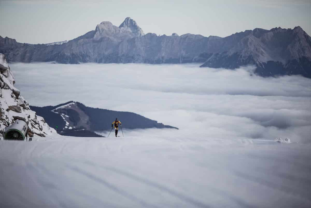 Ein Skibergsteiger gleitet durch den Schnee über Wolkenmeer in den Alpen.