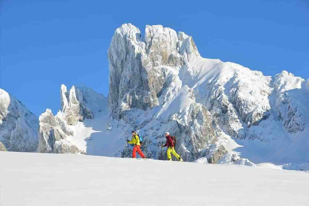 Skitourengeher genießen die alpine Winterlandschaft mit schneebedeckten Gipfeln im Hintergrund.
