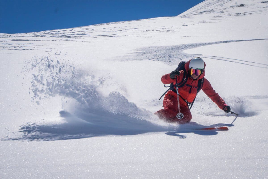 Skifahrer carving durch frischen Schnee in den beeindruckenden Alpen.