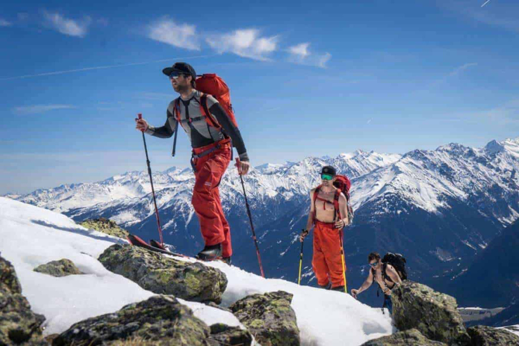 Skitourengeher wandern über schneebedeckte Berge in den Alpen unter klarem blauen Himmel.
