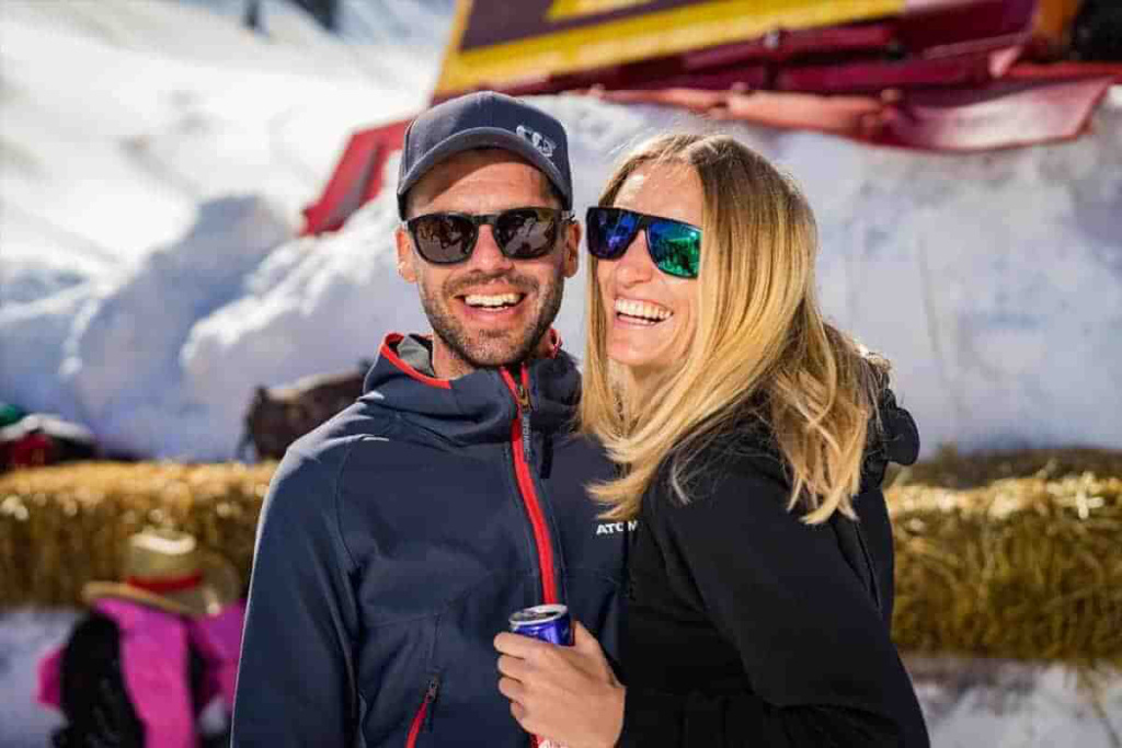 Lächelnde Menschen in Winterkleidung genießen eine sonnige Zeit im Schnee.