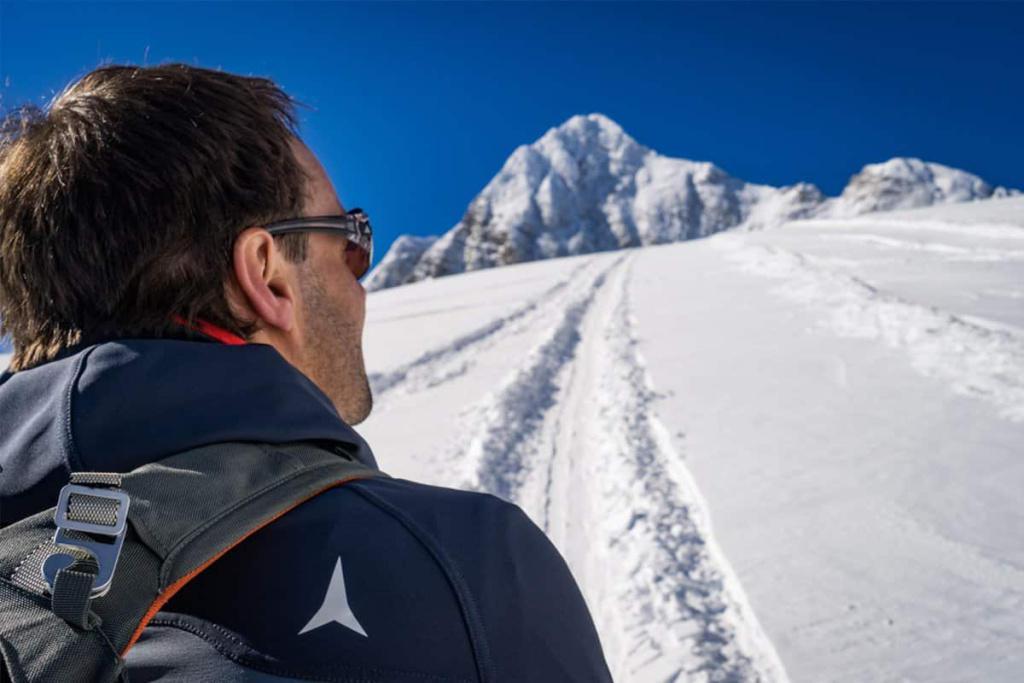 Bergwanderer auf einer verschneiten Piste mit Gipfelblick in den Alpen. Skitouren Abenteuer.