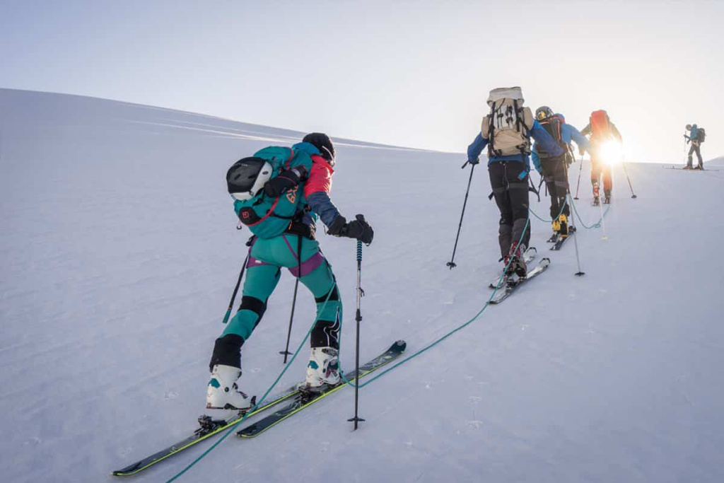 Skifahrer beim Anstieg auf einer verschneiten Piste in den Alpen.