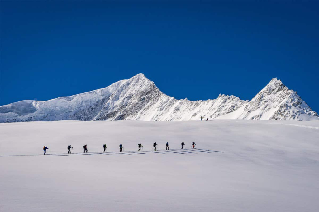 Skitourengeher im verschneiten Gebirge mit klar blauem Himmel. Abenteuer im Winter.