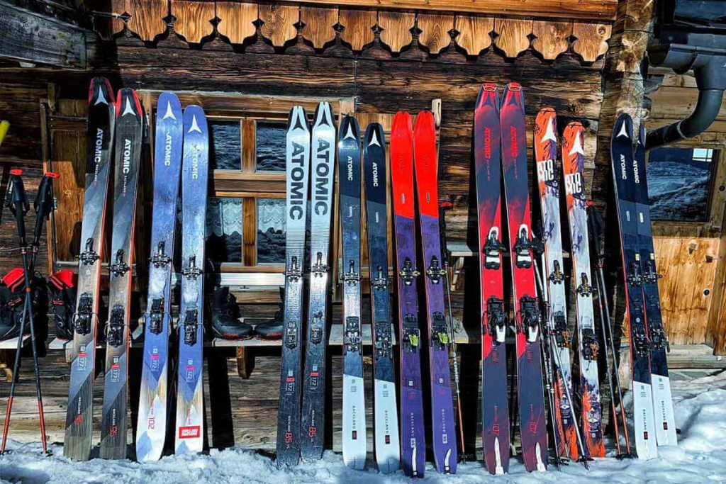 Vielfältige Skier und Stöcke vor einer Berghütte im Schnee für unvergessliche Skitouren.