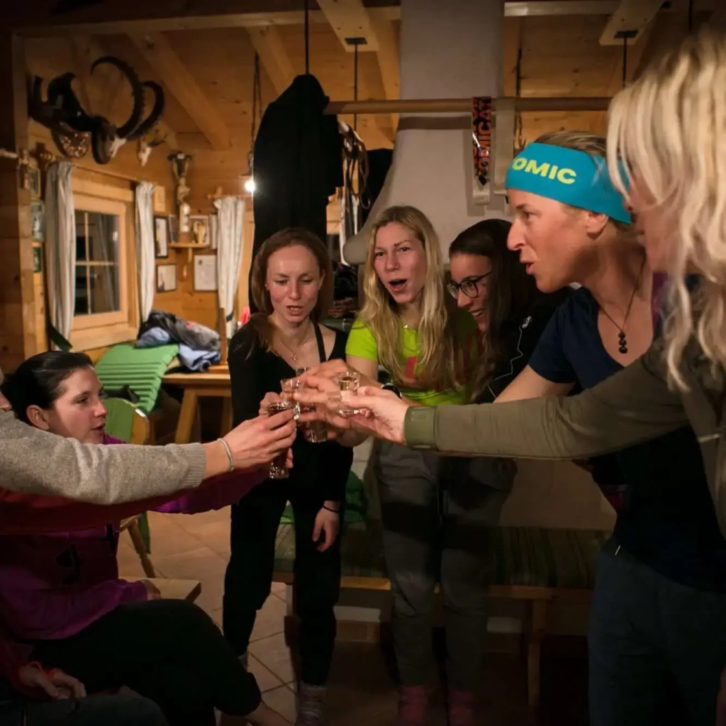 Gruppe feiert mit Gläsern in einer gemütlichen Hütte nach einem Skiabenteuer.