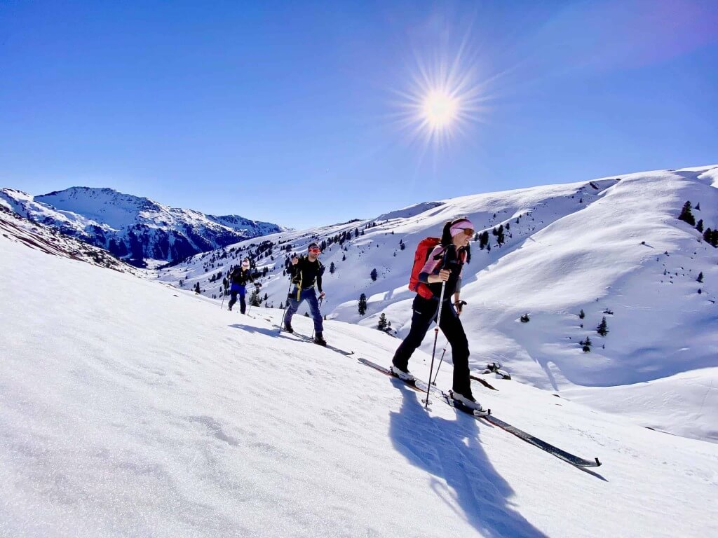 Skibergsteiger absolvieren eine geführte Tour durch verschneite Alpenlandschaft.
